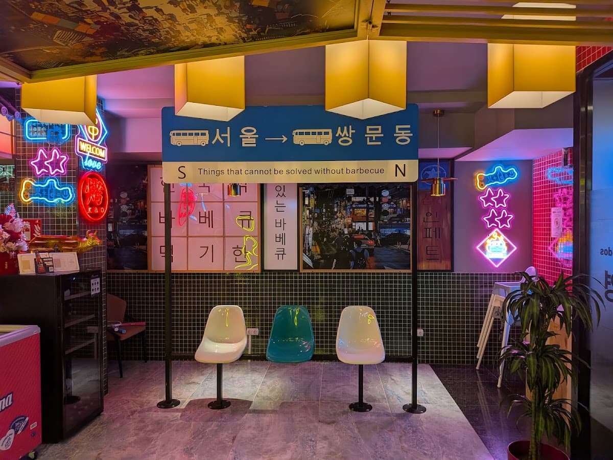 Reservado con luces de neón y decoración de calle coreana en Gogi Parrilla