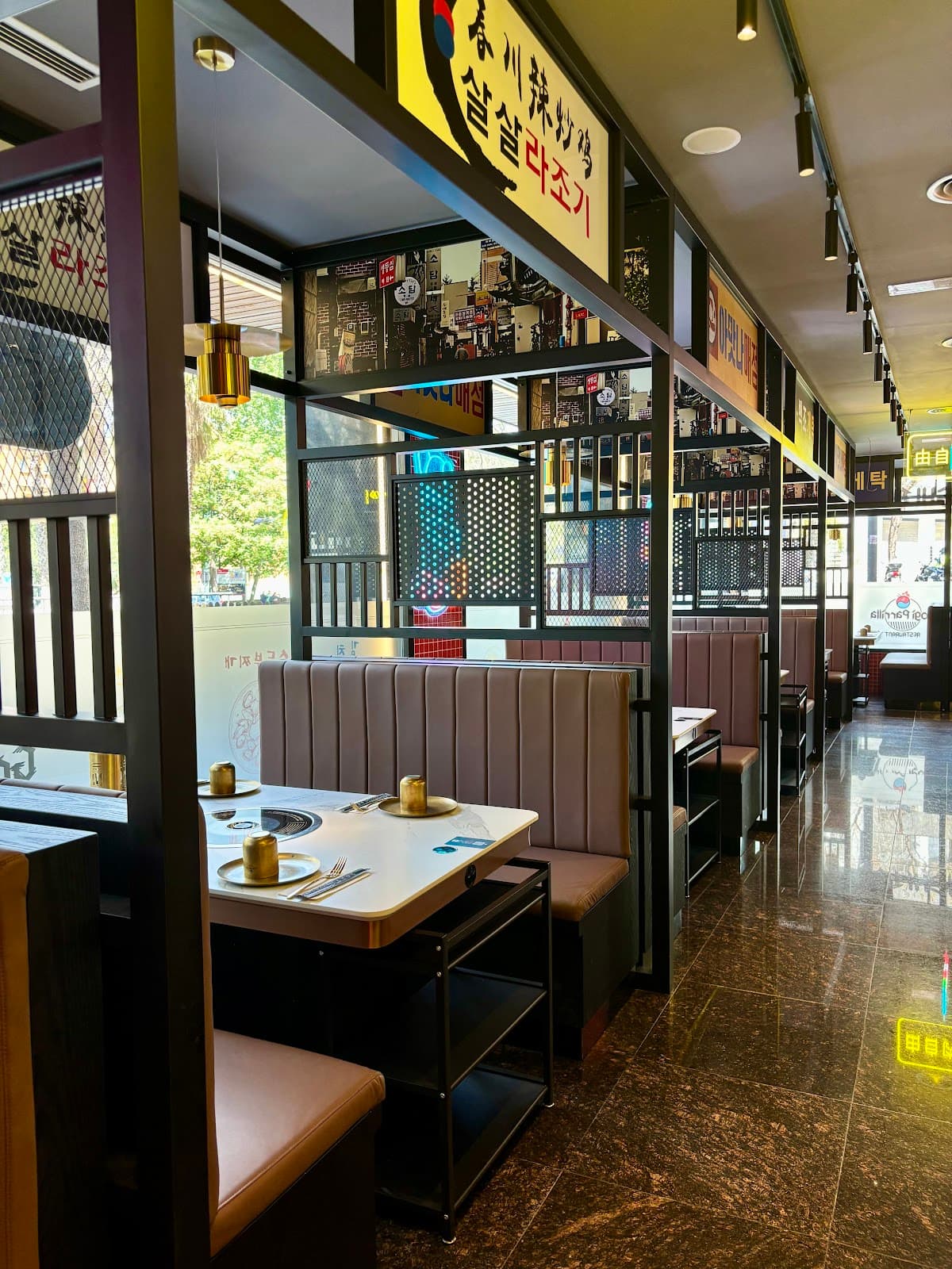 Interior de Gogi Parrilla en Tarragona con reservados de estilo coreano, neones y mesas equipadas con parrilla